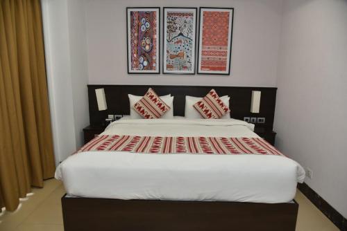 a bedroom with a large bed with red pillows at Ramada Encore by Wyndham Statue of Unity in Kevadia