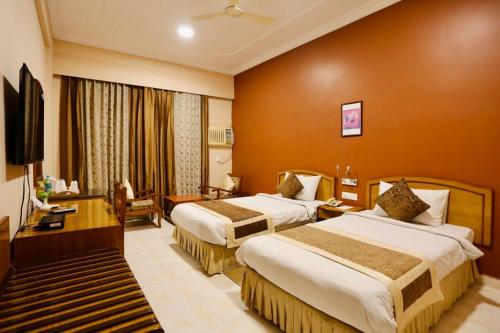 um quarto de hotel com duas camas e uma televisão em The Imperial Kushinagar em Kushinagar