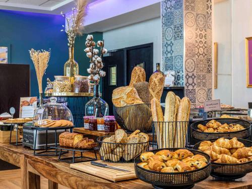 a table topped with baskets of bread and pastries at Mercure Paris Porte d'Orleans in Montrouge