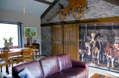 una sala de estar con sofá y una pintura de vacas en De Deel - Vakantiehuisje Veluwe en Ede