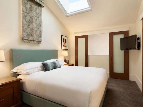 a bedroom with a white bed and a skylight at The Fairmont Heritage Place Ghirardelli Square in San Francisco