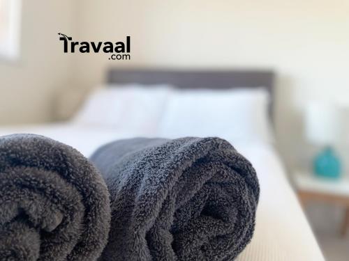 einen Stapel Handtücher auf dem Bett in der Unterkunft Travaal.©om - 2 Bed Serviced Apartment Farnborough in Farnborough