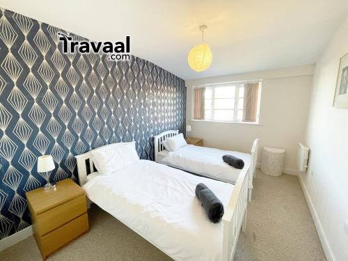 1 Schlafzimmer mit 2 Betten und einer Wand in der Unterkunft Travaal.©om - 2 Bed Serviced Apartment Farnborough in Farnborough