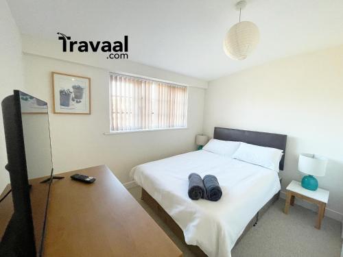 a bedroom with a bed with two black shoes on it at Travaal.©om - 2 Bed Serviced Apartment Farnborough in Farnborough