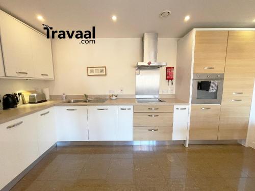 cocina con armarios blancos y nevera en Travaal.©om - 2 Bed Serviced Apartment Farnborough, en Farnborough