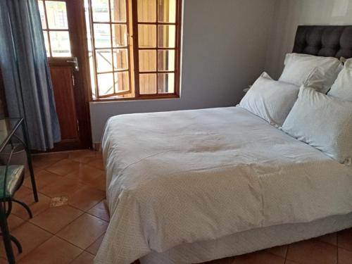 a bedroom with a large white bed with two windows at Pendleberry Holiday Resort - Unit 40 in Bela-Bela