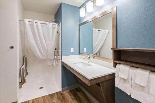 a bathroom with a sink and a mirror at WoodSpring Suites Broken Arrow in Tulsa