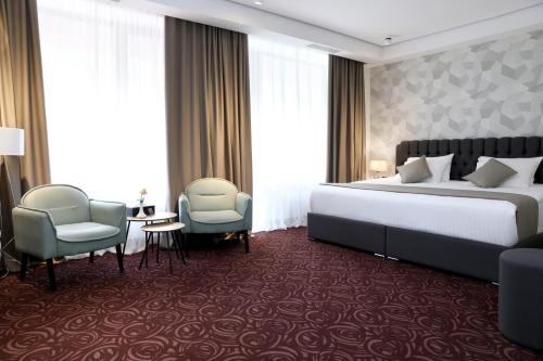 a hotel room with a bed and two chairs at Best Western Plus Paradise Hotel Dilijan in Dilijan