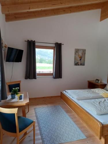 a bedroom with a bed and a table and a window at B&B Margit's Ranch Urlaub am Pferdehof in Silz