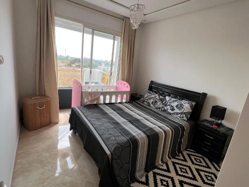 1 dormitorio con 1 cama con cuna y ventana en Résidence RAMOFLORES - Appartement avec piscine - Sidi Rahal, en Sidi Rahal