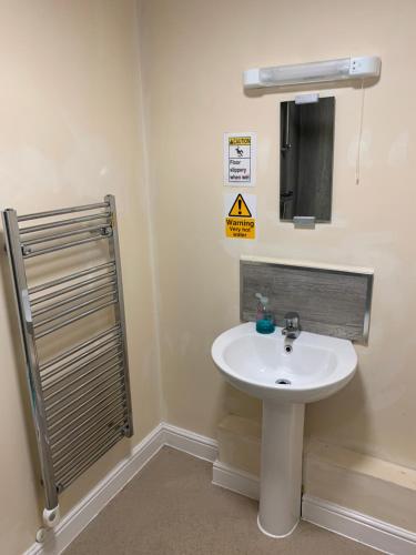 a bathroom with a white sink and a sign on the wall at Stonehenge Hostel - YHA Affliated in Amesbury