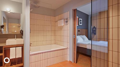 a bathroom with a tub and a sink and a bed at Grandi by Center Hotels in Reykjavík