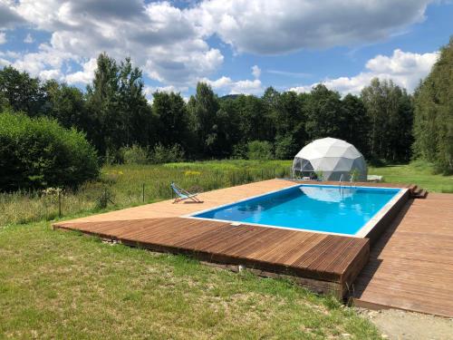 a swimming pool with a dome tent in a field at Glamping Stodoła Dome in Ściegny