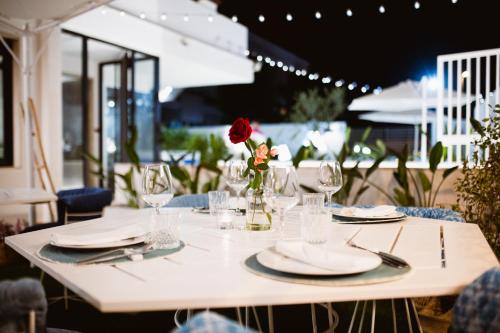 une table avec des assiettes et des verres et une rose dans un vase dans l'établissement Hotel Riviera, à Bari