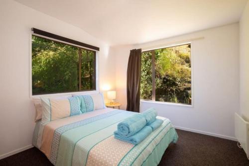 a bedroom with a bed and two windows at Alpine Escape - Elevated Views with Spa in Queenstown