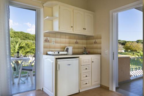 a kitchen with white cabinets and a view of a patio at Panorama Fanari studios and apartments in Argostoli