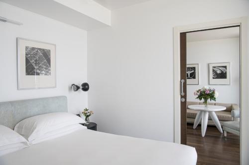 a bedroom with a bed and a table and a mirror at Excelsior Hotel, SPA & Lido - Preferred Hotels & Resorts in Pesaro