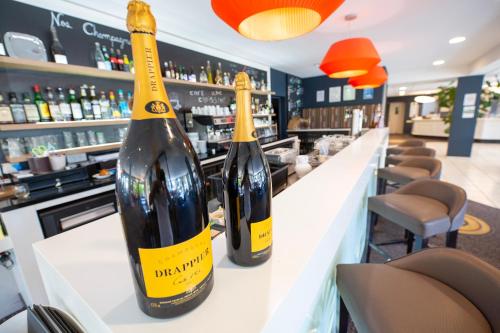 two bottles of wine sitting on a counter in a bar at Hostellerie Saint Vincent Beauvais Aeroport in Beauvais