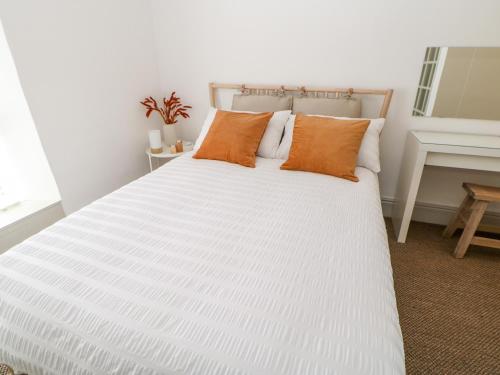 ein weißes Bett mit orangefarbenen Kissen im Schlafzimmer in der Unterkunft Dale Cottage in Darlington
