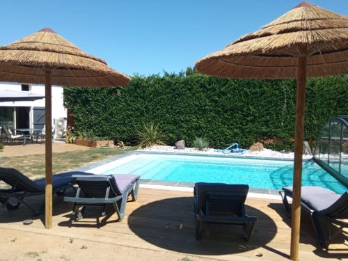 a group of chairs and umbrellas next to a pool at Mas des Vignes Piscine chauffée in Le Champ-Saint-Père