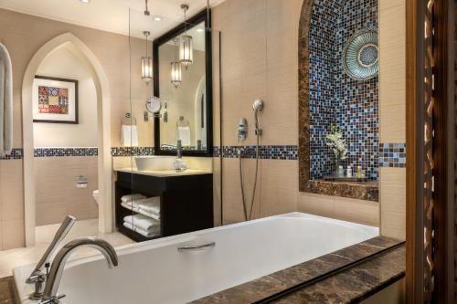 a bathroom with a tub, sink, mirror and bathtub at Oaks Ibn Battuta Gate Dubai in Dubai