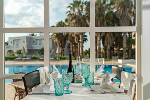 a table with a bottle of wine and glasses on it at Delfina Tropic Beach in Georgioupolis