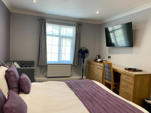 a bedroom with a bed and a desk and a television at Exeter Court Hotel in Exeter