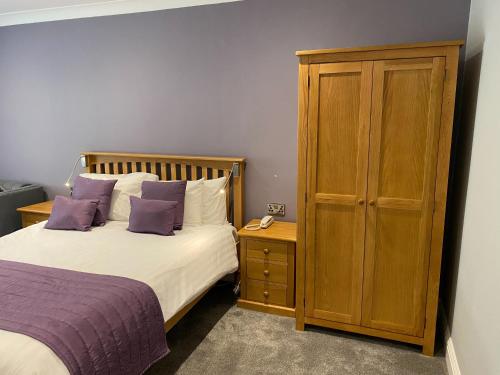 a bedroom with a bed and a wooden cabinet at Exeter Court Hotel in Exeter