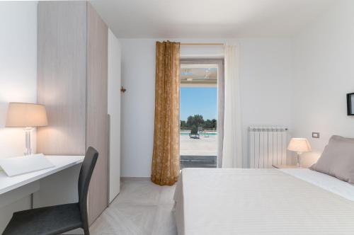 a bedroom with a bed and a desk and a window at Villa Gioena con piscina in San Vito dei Normanni