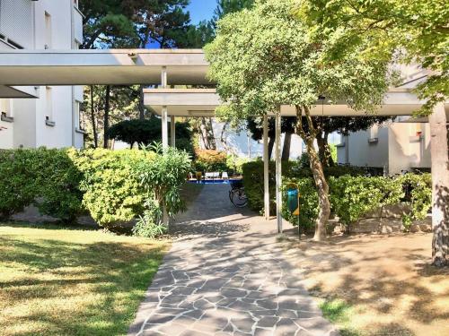 una pasarela frente a un edificio con un árbol en TARTANA, en Lignano Sabbiadoro