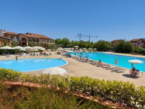 uma grande piscina com guarda-sóis e pessoas sentadas à sua volta em Resort il cigno em Peschiera del Garda