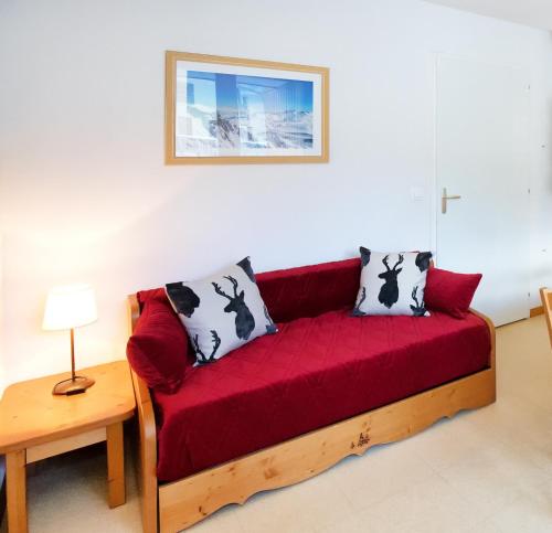 a red couch in a living room with a table at Les Balcons PROCHE PARC NATIONAL VANOISE appartements 2 pieces 5 pers in Termignon