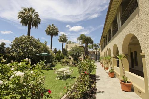 a garden next to a building with palm trees at Quality Hotel Mildura Grand in Mildura