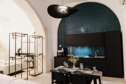 a kitchen with a table and a green wall at I Dammusi di Via Vittorio Veneto in Syracuse