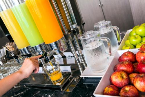 a person is making a drink on a counter with apples at Holiday Inn Express Jakarta International Expo by IHG in Jakarta