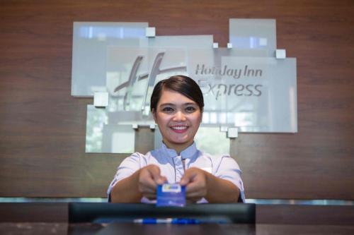 a woman holding a cell phone in her hands at Holiday Inn Express Jakarta International Expo by IHG in Jakarta