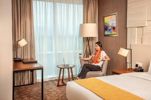 a woman sitting in a chair in a hotel room at Crowne Plaza Bandung by IHG in Bandung