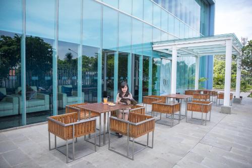 a woman sitting at a table in front of a building at Holiday Inn Express Jakarta International Expo by IHG in Jakarta