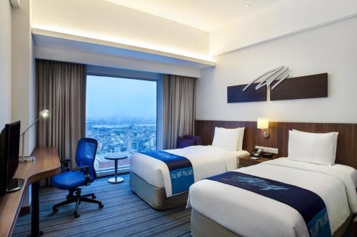 a hotel room with two beds and a desk at Holiday Inn Express Jakarta Pluit Citygate by IHG in Jakarta