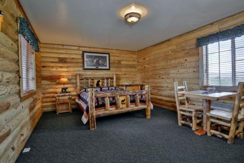 Schlafzimmer mit Holzwänden, einem Bett und einem Schreibtisch in der Unterkunft Wolf Den Log Cabin Motel and RV Park in Thayne