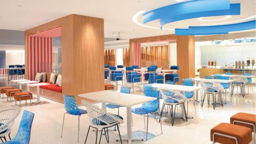 a restaurant with white tables and blue chairs at Holiday Inn Express Baruna by IHG in Kuta