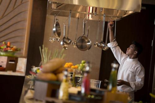 a man in a kitchen holding up a pot at InterContinental Bandung Dago Pakar by IHG in Bandung