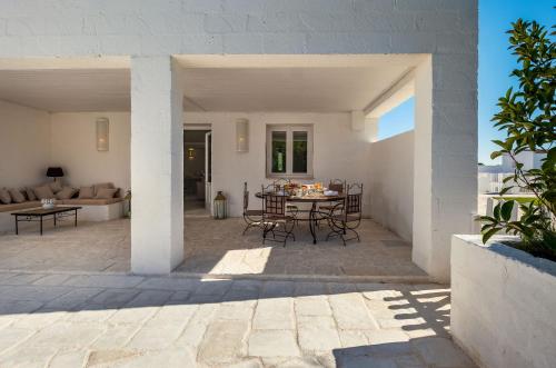 eine Terrasse mit einem Tisch, Stühlen und einem Sofa in der Unterkunft Baglioni Masseria Muzza in Otranto