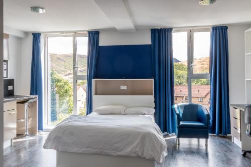 a bedroom with blue curtains and a bed and a chair at Destiny Student - Holyrood (Brae House) in Edinburgh