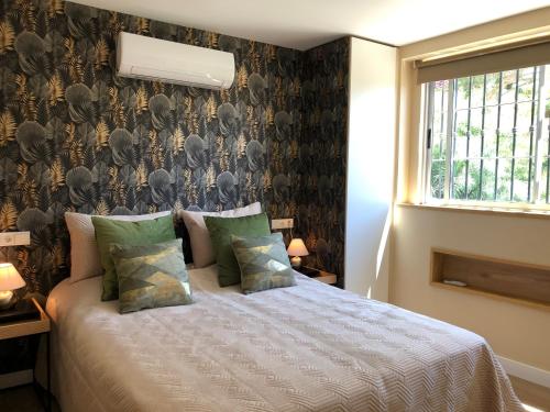 a bedroom with a bed and a wall covered in wallpaper at Maravilloso Guesthouse in Fuengirola