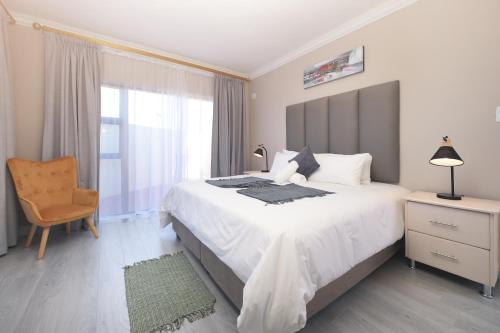 a bedroom with a large white bed and a chair at King Guest Lodge in Port Elizabeth
