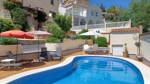 una piscina con sedie e ombrelloni accanto a una casa di Maravilloso Guesthouse a Fuengirola
