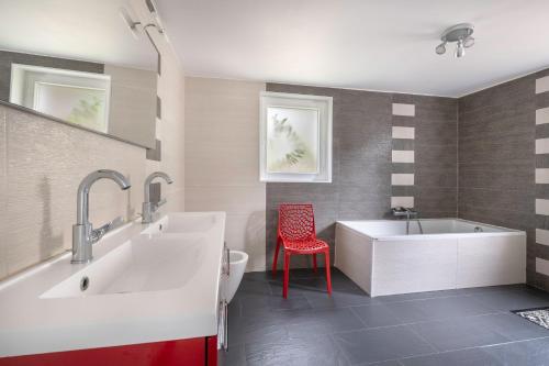 a bathroom with two sinks and a tub and a red chair at Magnifique maison avec piscine in La Baule