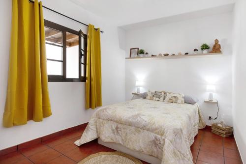 a bedroom with a bed and a window with yellow curtains at Casa Diego in Soo