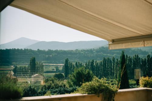 a view from a window with trees and mountains in the background at Clos Saint-Michel Resort & Spa in Malaucène
